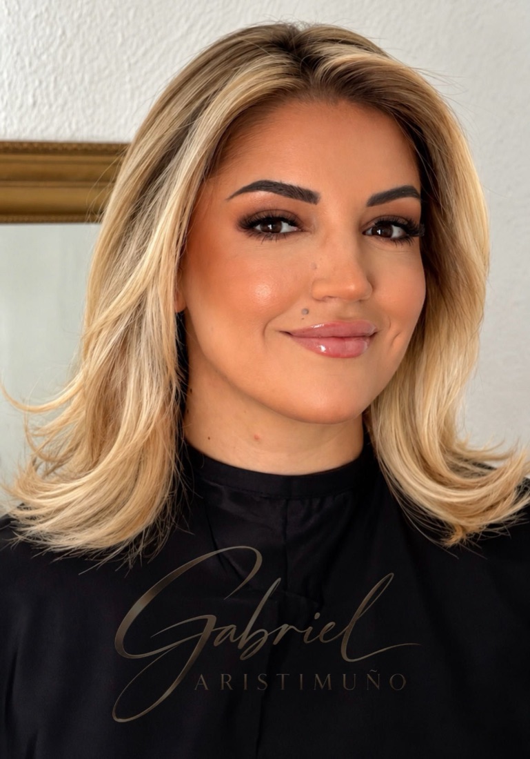 Clienta con melena rubia con mechas y maquillaje completo, de frente.