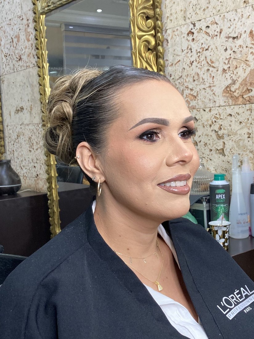 Clienta de perfil con un recogido pulido y maquillaje completo.