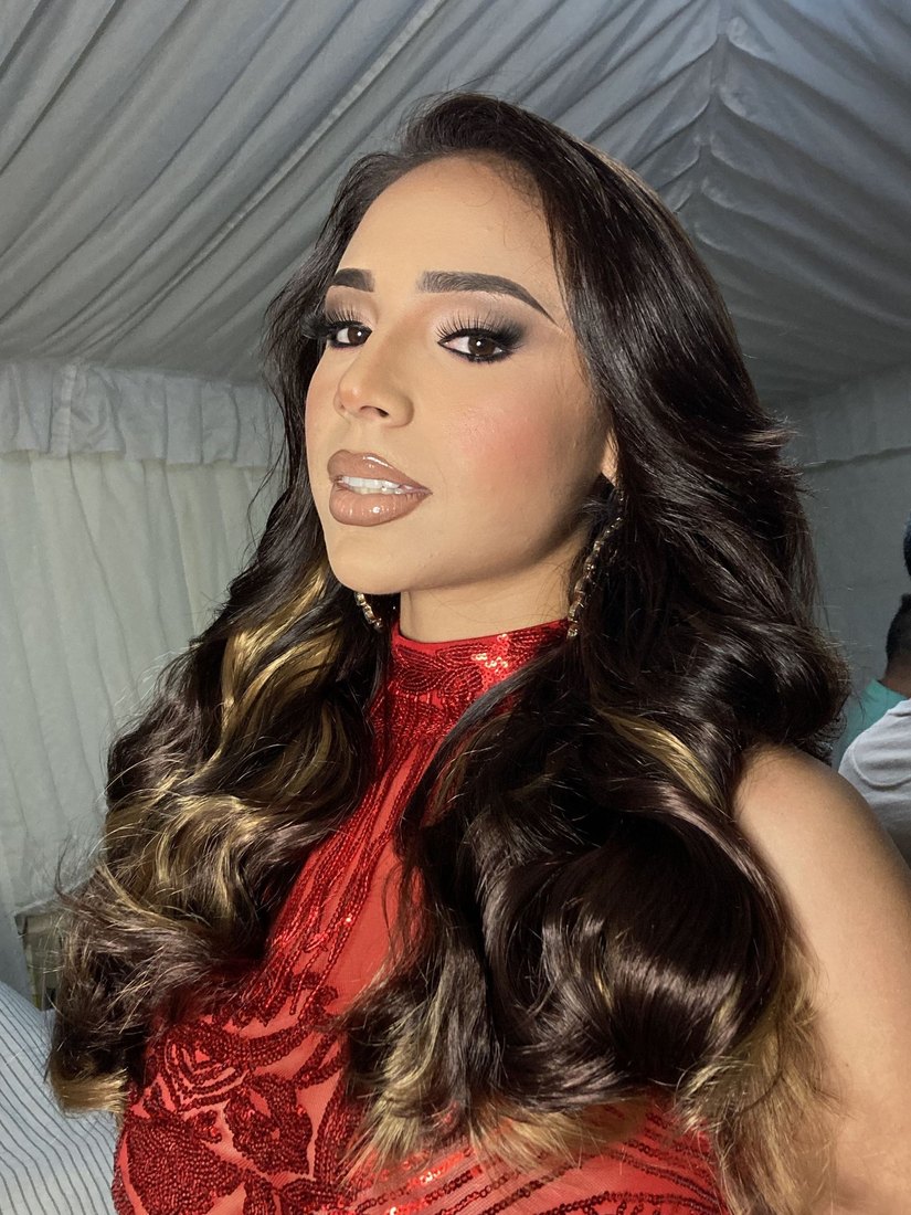 Clienta con maquillaje de noche y melena castaña con reflejos en ondas, con vestido rojo de lentejuelas.
